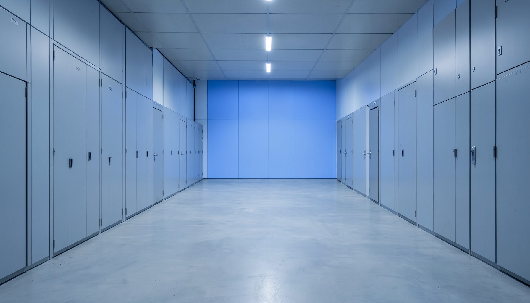 A wide atmospheric photograph of a secure storage facility interior with soft blue-gray tones, clean lines, and a sense of quiet strength.