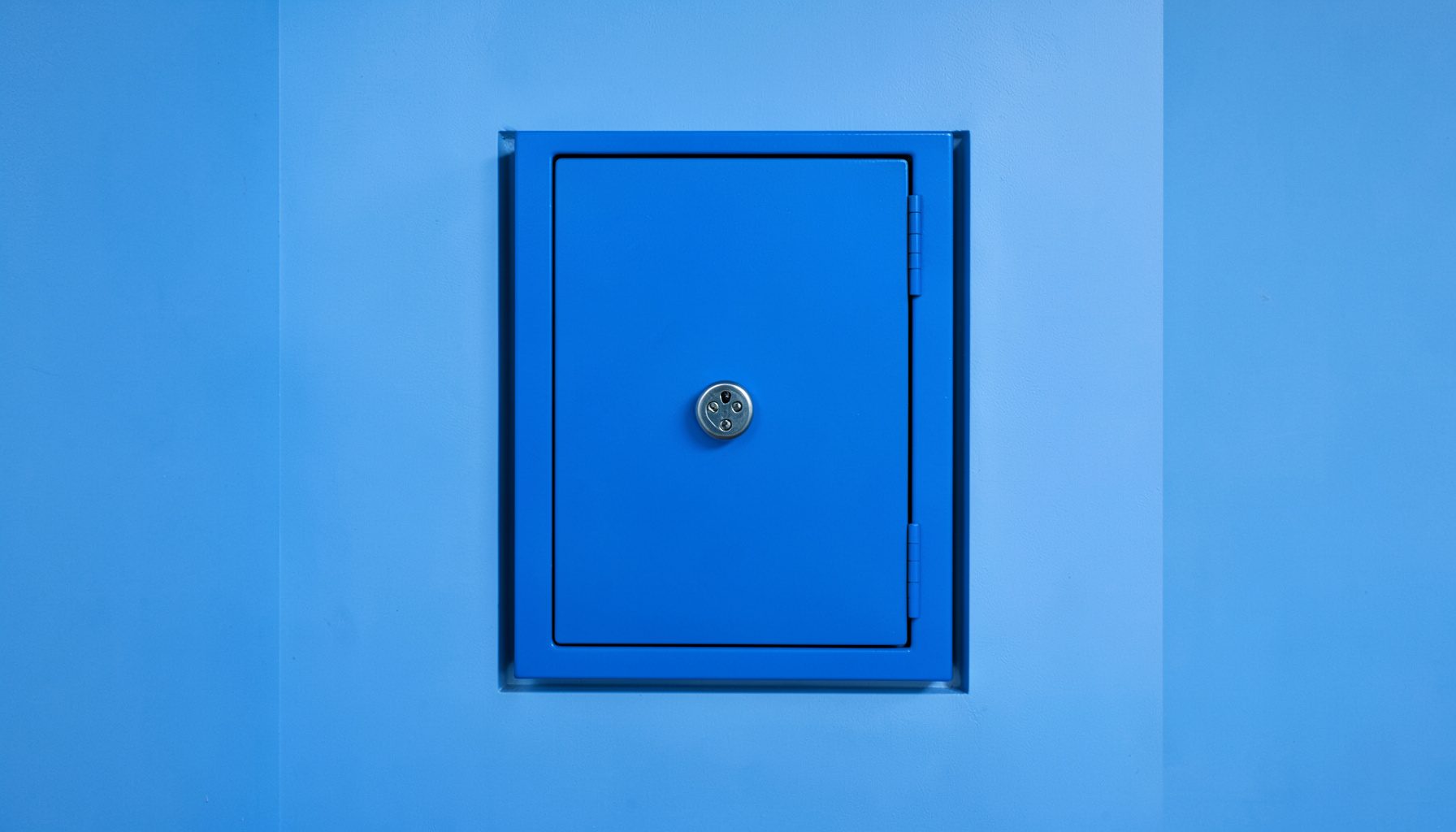 A recessed wall gun safe installed between studs, painted to match the surrounding wall, with a concealed magnetic lock
