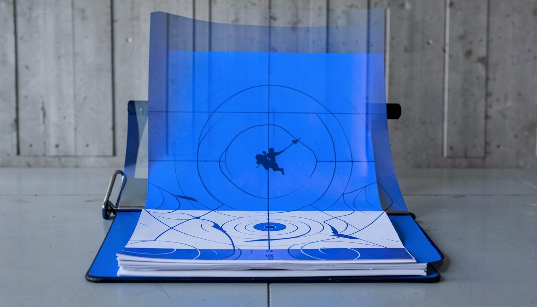 A stack of paper shooting targets with silhouette and bullseye patterns, arranged on a clipboard against a range wall